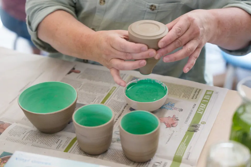 Een zelfgemaakte beker en kommen met groene glazuur
