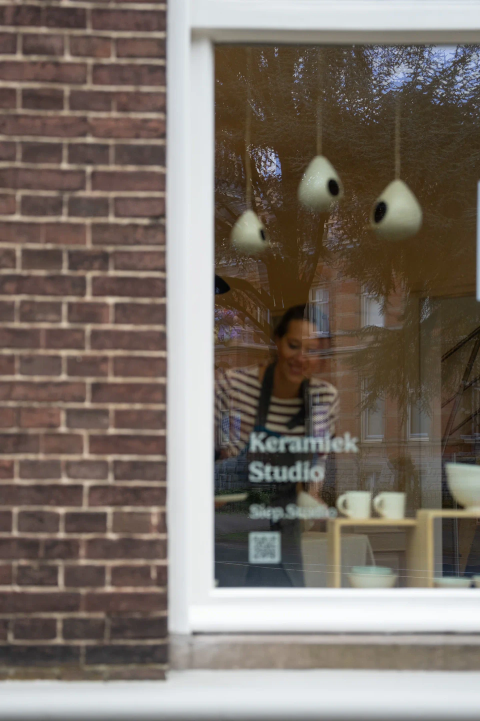 Siep aan het werk achter het raam van haar keramiekatelier