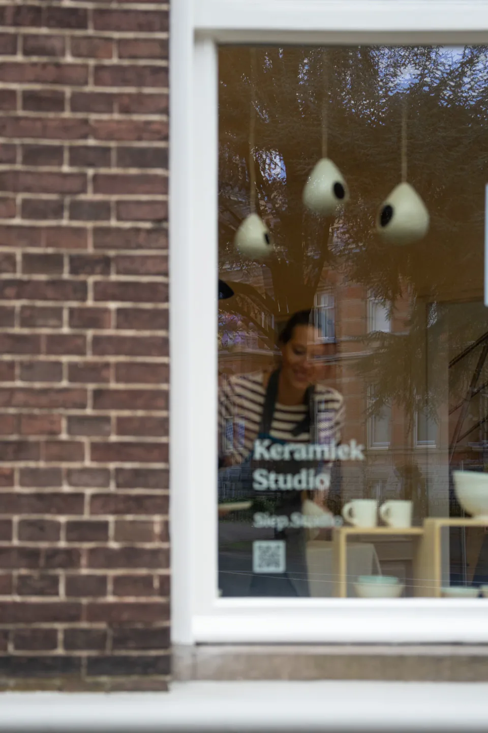 Siep aan het werk achter het raam van haar keramiekatelier