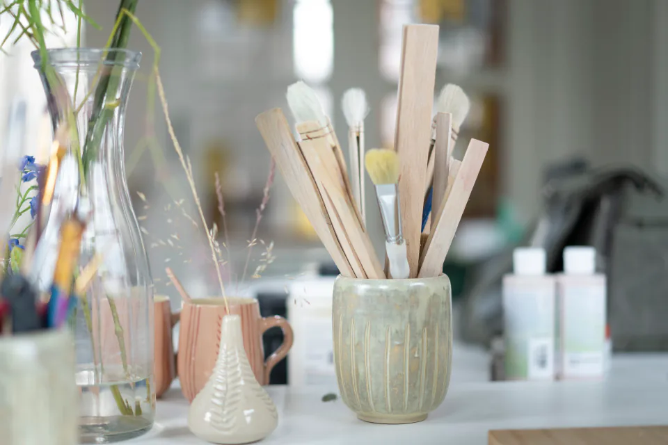 Kwasten en houten gereedschap in een keramieken pot in het atelier